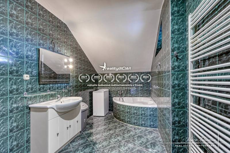 A bathroom with green tiles and white sanitary ware in a family house.