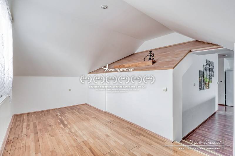 Attic room with white walls and a wooden decor floor in a family house.