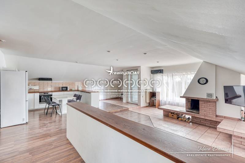 Living room with a fireplace and kitchen area, wooden decor flooring, bright room.