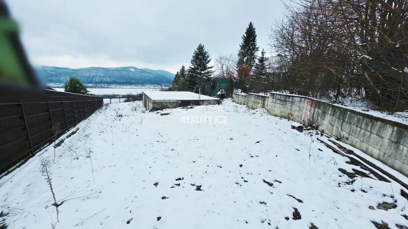 Snow-covered recreational plots in Považská Bystrica with a view of the surrounding mountains.