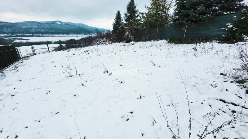 A snow-covered area in the Recreational Grounds near Považská Bystrica, bordered by a fence and trees.