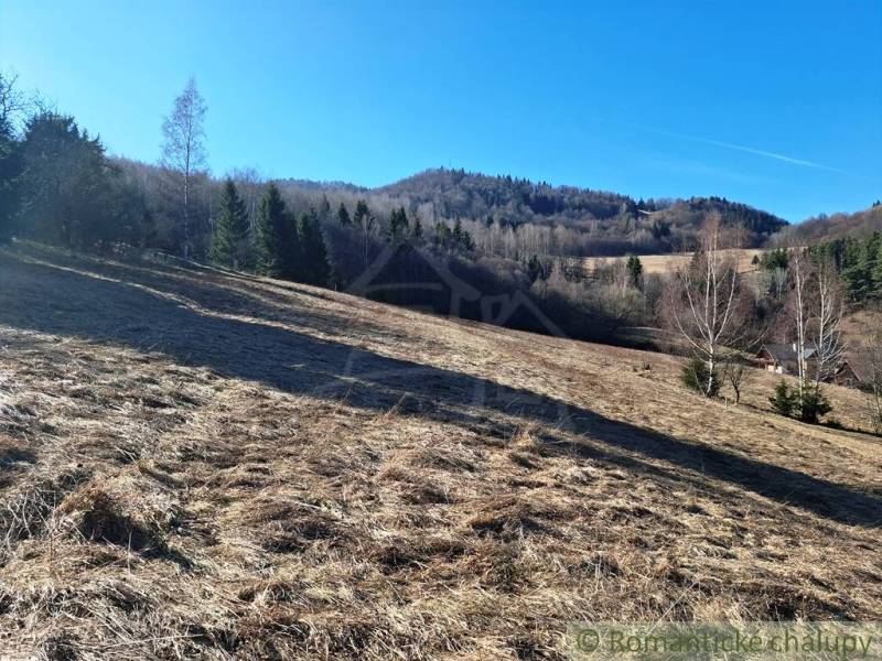 Agricultural and forest land in Hronec with grassy hills and trees in the background.