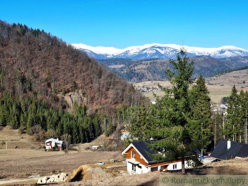 Snow-covered mountains and cottages surrounded by forests and farmland near Hronec.