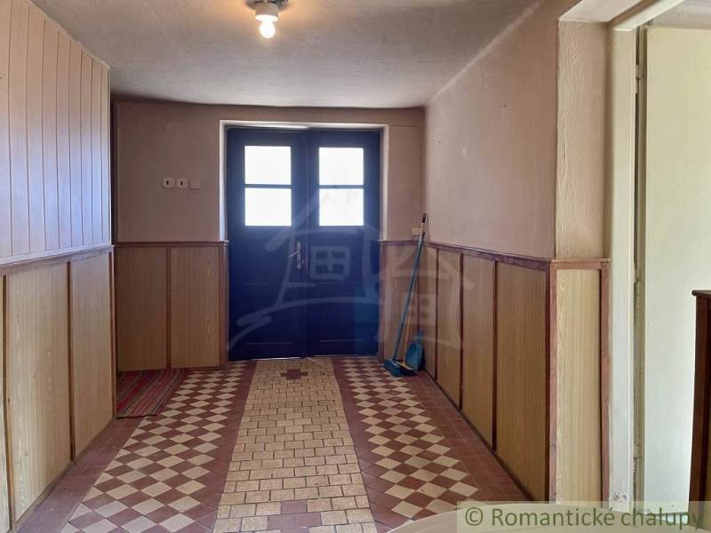 Entrance hall of a family house with a colorful floor and wooden paneling on the walls.