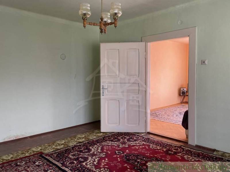 A room in a family house with a carpet, white doors, and a chandelier.