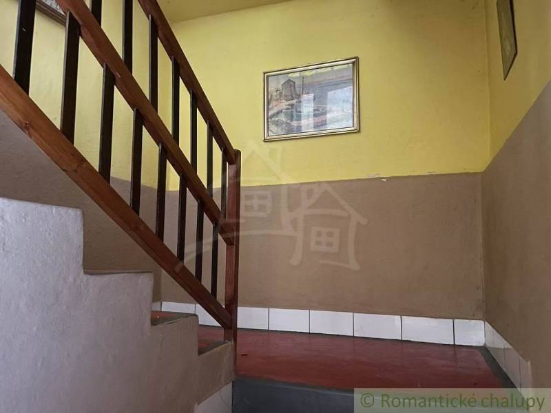 A staircase with a wooden railing in a family house with yellow walls and a painting.