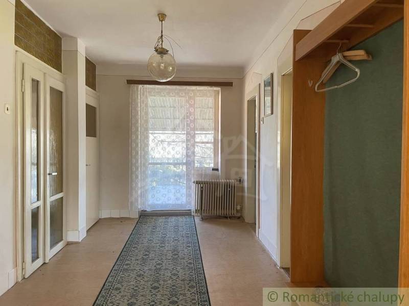 Interior of a family house with a wood-patterned floor, curtain, and carpet.