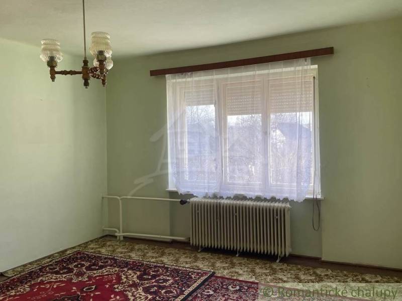 A bright room in a family house with a carpet, radiator, and curtains.