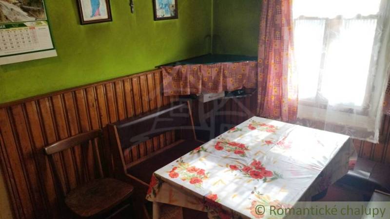 A room in a family house with wooden paneling, a floral tablecloth, and curtains.