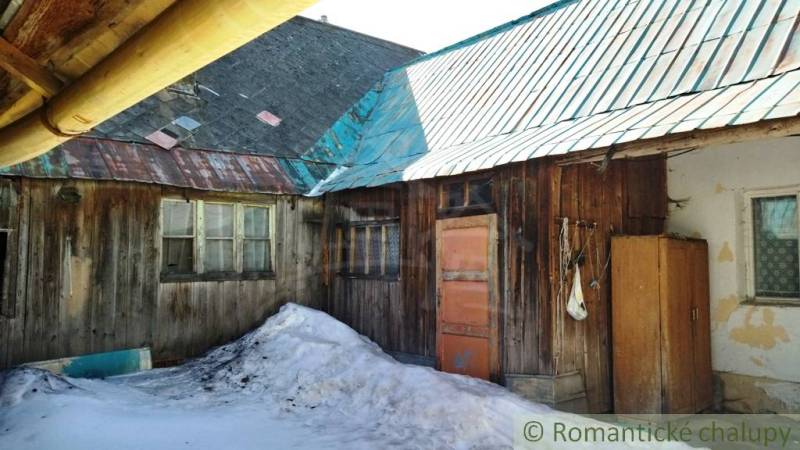 A wooden family house in Osturňa with snow-covered ground and a metal roof.