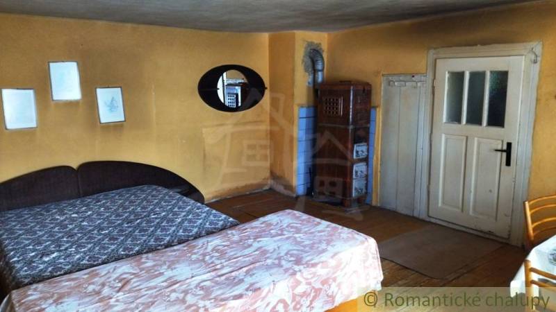 Rustic room with a tiled stove and beds in a family house.