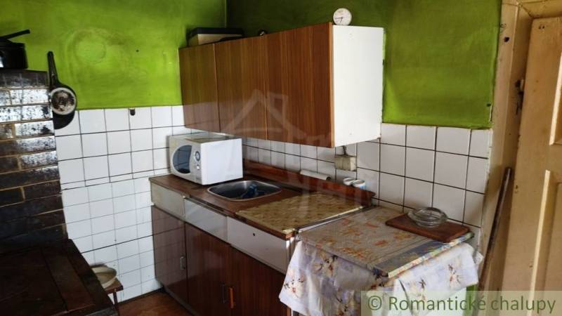 A kitchen in a family house with a wooden cabinet, a sink, and a microwave oven.