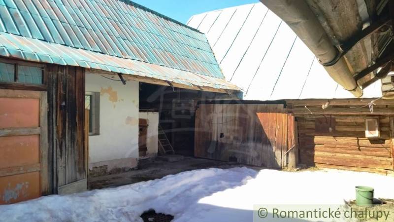The courtyard of a family house in Osturňa with a wooden shelter and a snow-covered plot.