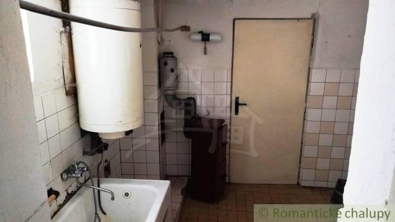 Bathroom with a bathtub, boiler, and tiles in a family house.