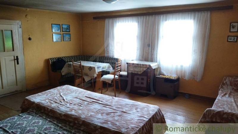 A cozy room with wooden decor, windows, a table, and a bed in a family house.