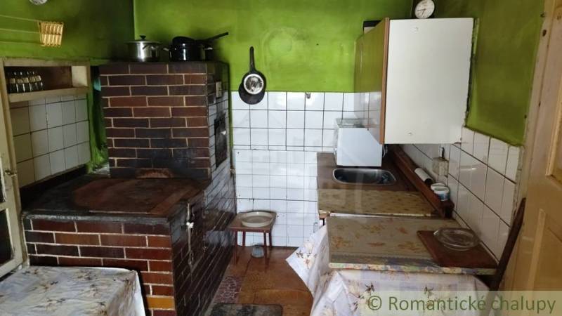 Rustic kitchen with a brick stove and green walls in a family house.