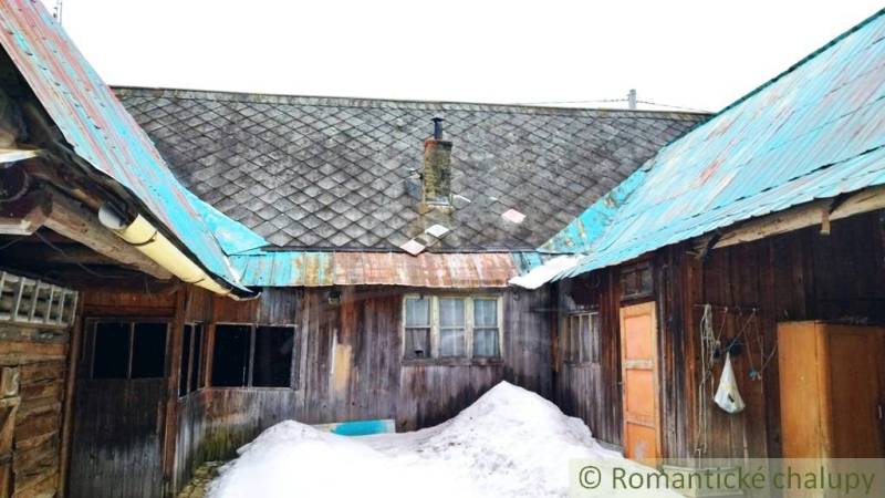 A wooden family house in Osturňa with a snowy yard and a tin roof.