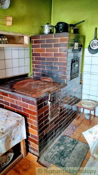 A kitchen in a family house with a traditional brick oven and dishes on the stove.
