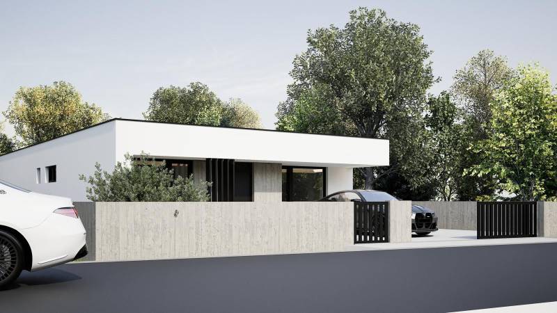 A family house in Nesvady with a white facade, a concrete fence, and lush greenery.