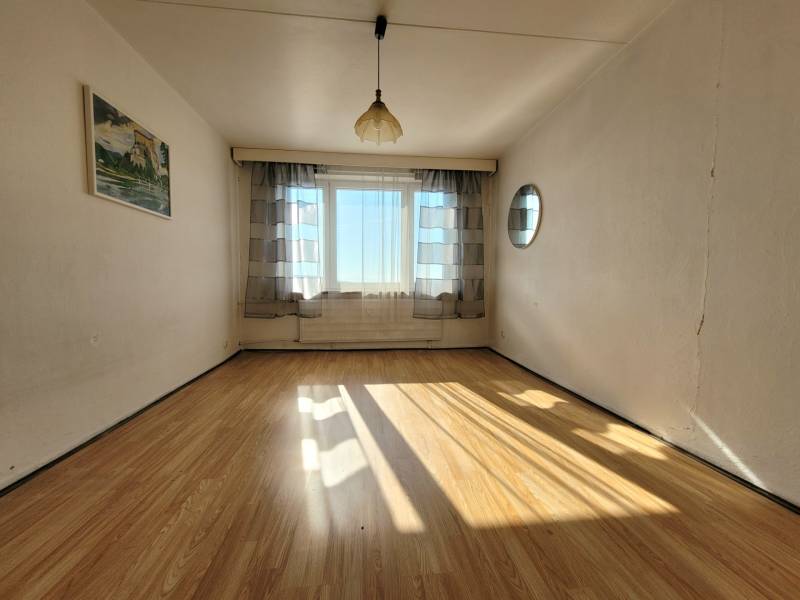 A bright room with a large window, curtains, and a wooden decor floor in a 2-room apartment.
