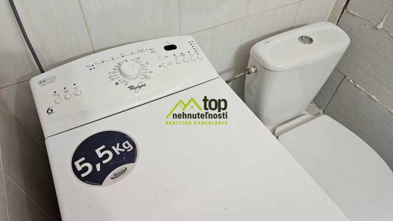 A washing machine next to the toilet in a studio apartment, suitable for everyday use.