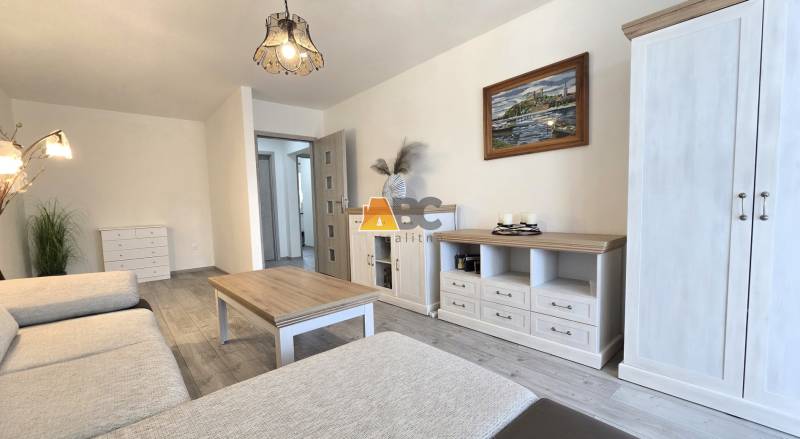 Living room in a 2-room apartment with light furniture and a wooden decor floor.