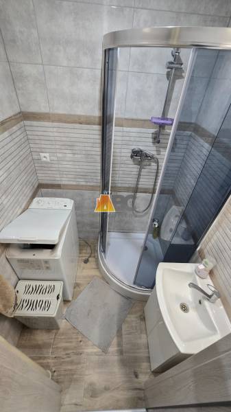 Bathroom with a shower and a sink in a 2-room apartment, floor with wood decor.