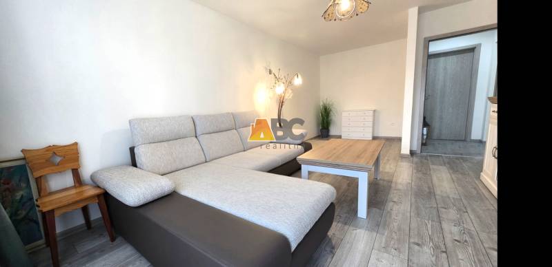 Living room with a sofa and wood-patterned flooring in a two-room apartment.