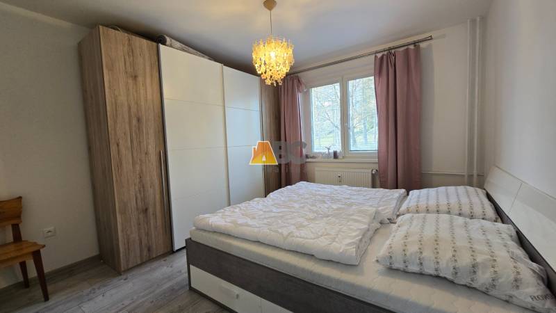 A bedroom in a 2-room apartment with a large wardrobe and a bed, floor with a wooden decor.