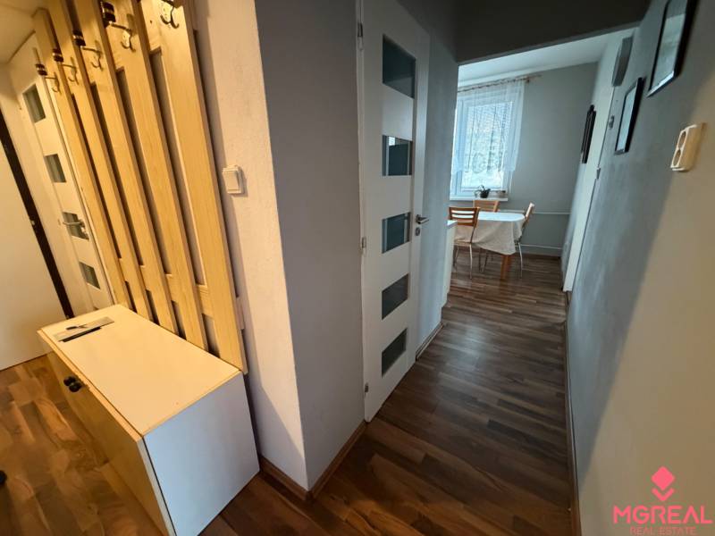 A hallway in a 3-room apartment with a wooden decor floor and a table by the window.