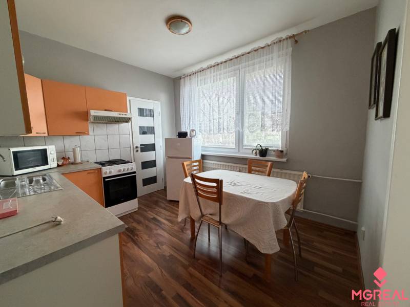 A kitchen with a dining table and a wooden decor floor in a 3-room apartment.