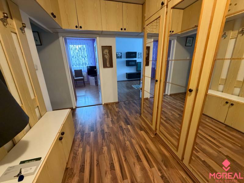A hallway in a 3-room apartment with a wooden decor floor and built-in wardrobes.