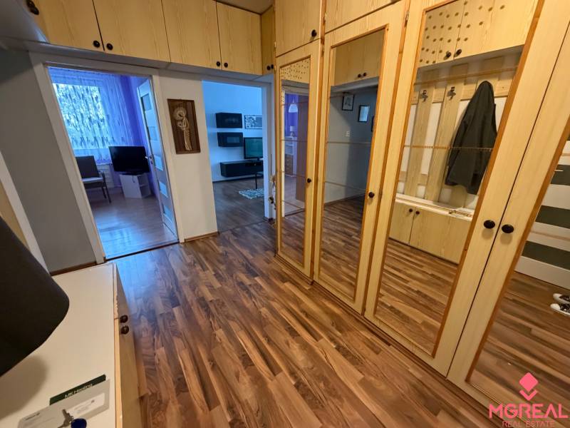 Entrance hall in a 3-room apartment with a wooden decor floor and mirrored wardrobes.