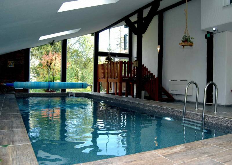 Interior of a holiday apartment with a wood-patterned floor and an indoor pool.