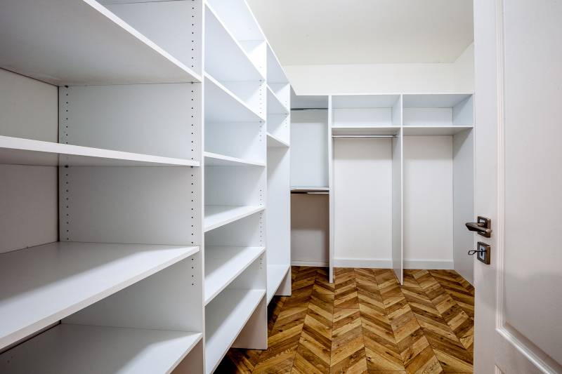 A wardrobe with white shelves and a wooden decor floor in a holiday apartment.