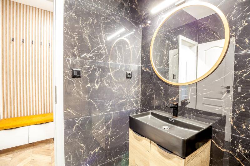 Bathroom in a Holiday Apartment with a black sink and a round mirror.