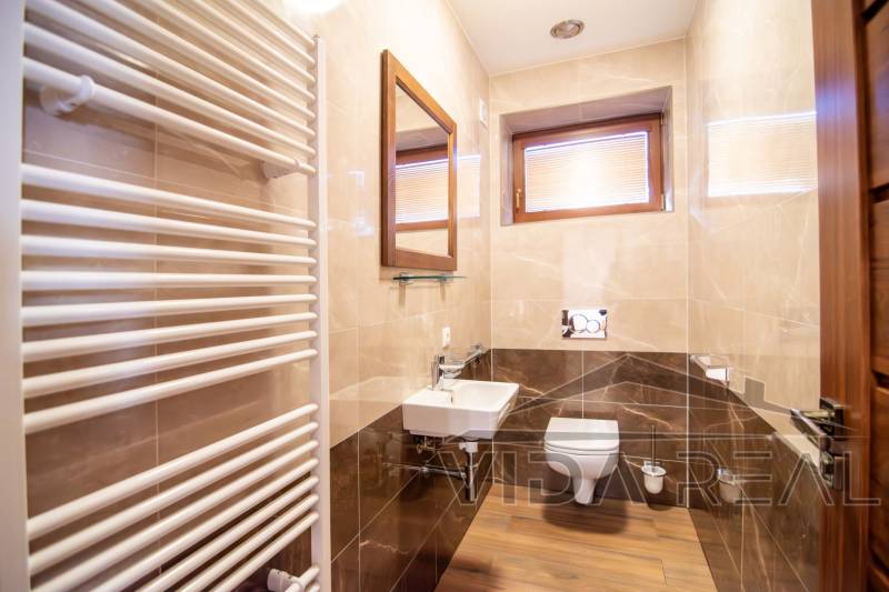 A bathroom in a family house with a wooden decor floor, a sink, and a heating element.