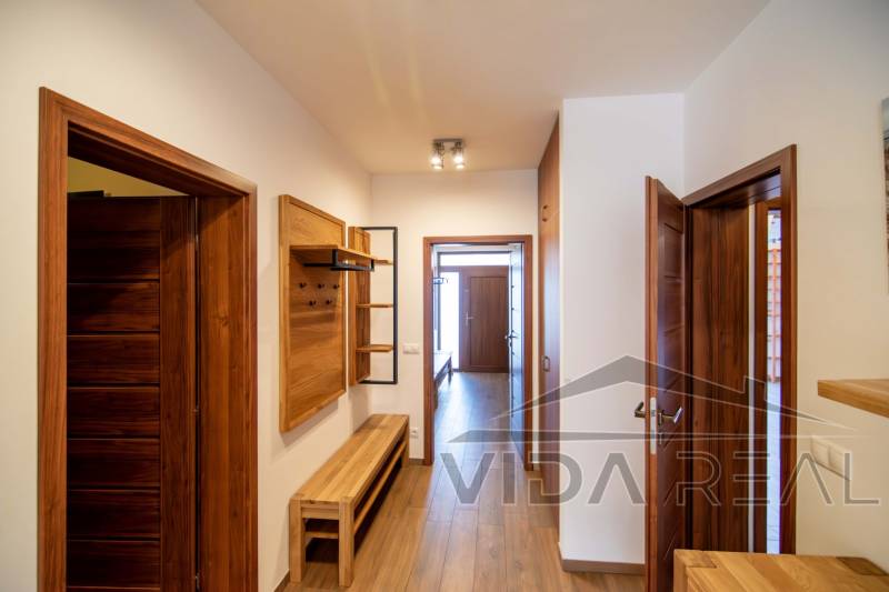 A hallway in a family house with wooden decor on the floor and furniture.