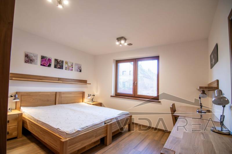 Bedroom in a family house with a bed, night lamps, and a wooden decor floor.