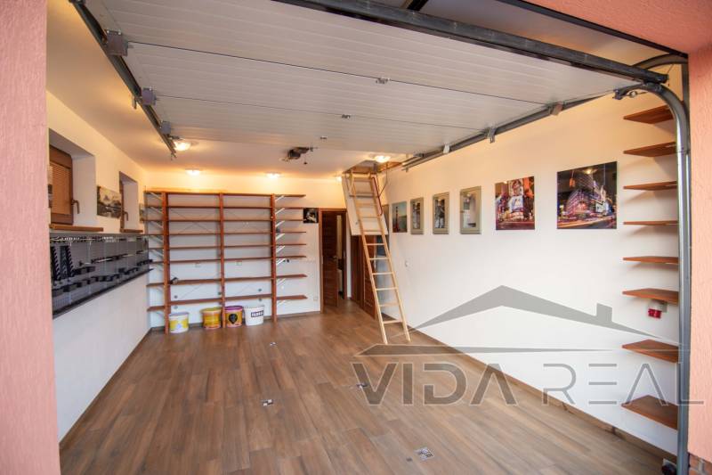 A garage in a family house with shelves, a wooden decor floor, and a retractable ladder.