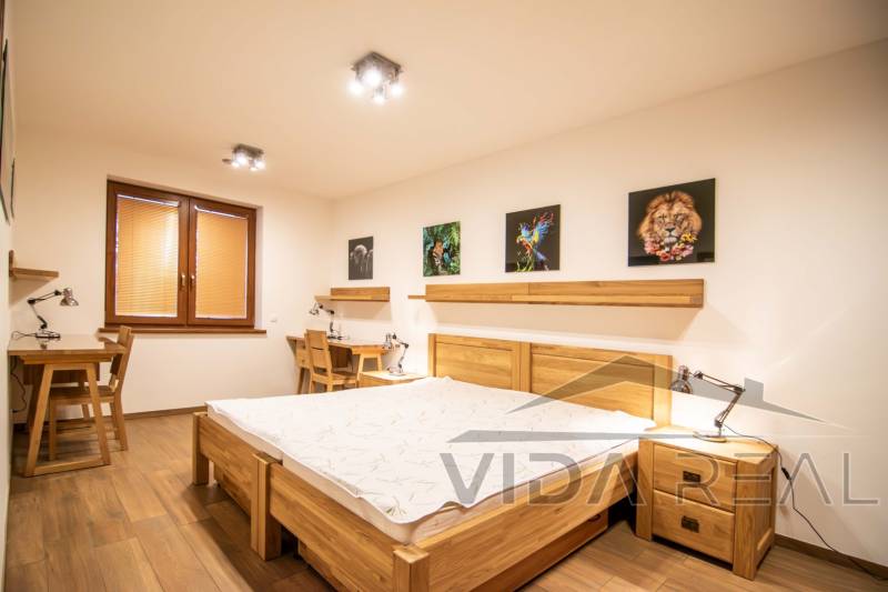 Bedroom in a family house with a wood-decor floor, paintings, and desks.