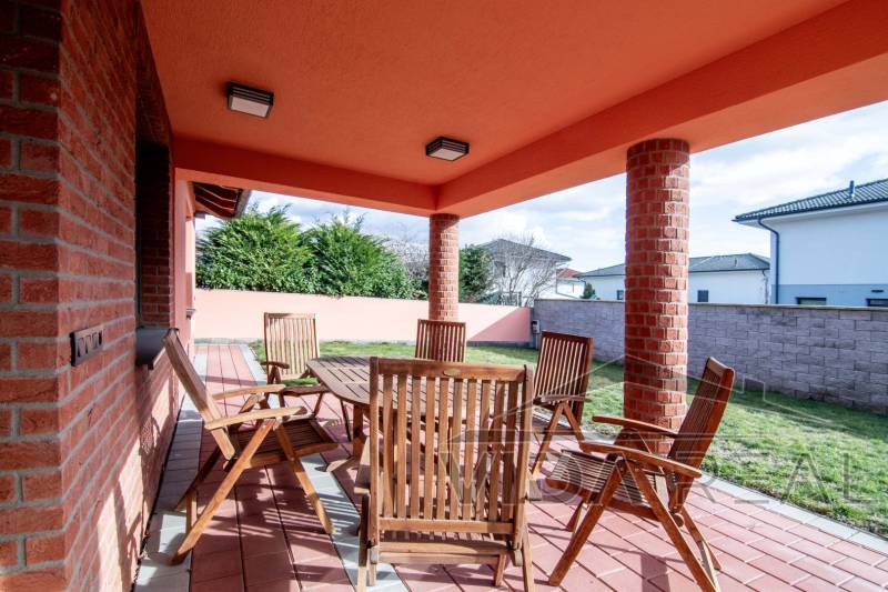 The terrace of a family house on Krajná Street in Stupava with wooden furniture and brick walls.