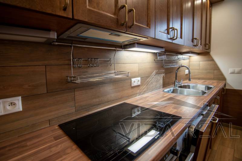 A kitchen in a family house with a wooden decor floor and a wooden kitchen unit.