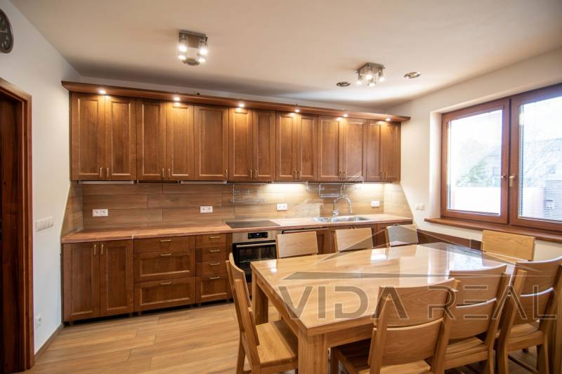 A kitchen in a family house with a wooden decor, equipped with wooden furniture and a dining table.