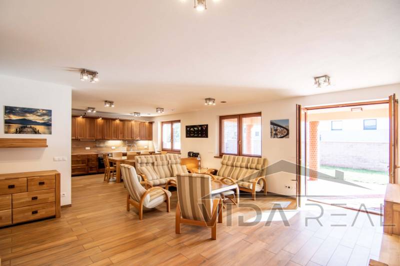 Living room with dining area and kitchen, wooden decor flooring, family house.