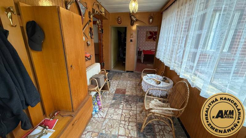 Interior of a family house with a tiled floor, wooden paneling, wicker furniture, and decorations.