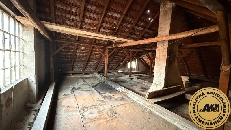 Attic in a family house with wooden beams and a large window.