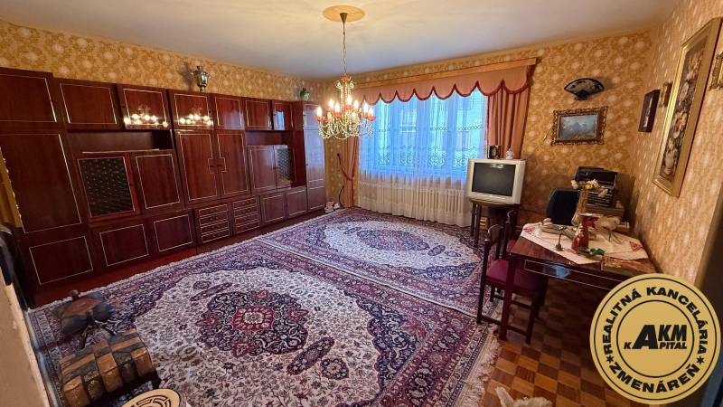 Living room in a family house with a carpet, an older television, and an elegant chandelier.