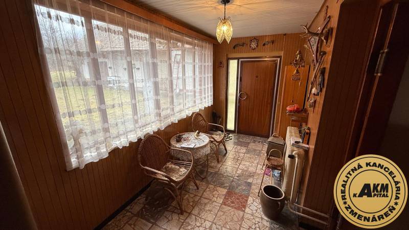 Entrance hall in a family house with rattan chairs and large windows.
