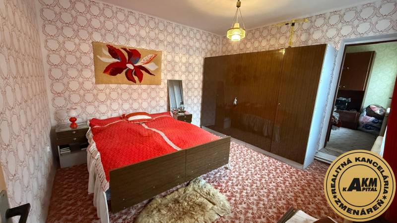 Bedroom in a family house with carpet, patterned wallpaper, and a large wardrobe.